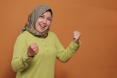 Kendine güvenen Müslüman bir kadın gururlu ve neşeli bir ifadeyle zafer jesti sergiliyor. Güçlendirme, motivasyon, başarı ve modern yaşam tarzı gibi konular için mükemmel.