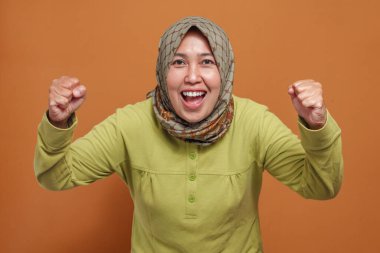 Heyecanlı Müslüman kadın zaferi neşeli bir yüz ifadesi ve enerjiyle kutluyor.