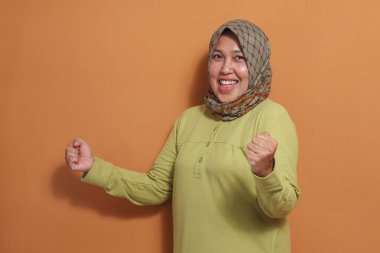 Neşeli Müslüman kadın zafer sevinci ve güven ifadesi gösteriyor