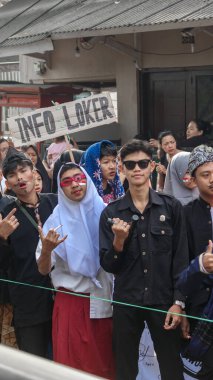 'JODOH MASIH BELUM TERLIHAT' da dahil olmak üzere mizahi işaretlerle Bağımsızlık Günü geçit töreninde eğlenen bir grup insan, neşeli ve neşeli bir atmosfer yaratıyor, Bandung - Endonezya, 17 Ağustos 2024
