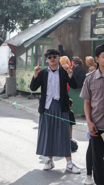 Kültür festivali sırasında el hareketi yapan etekli genç bir adam. Gençlerin güveni ve sokak modasını temsil eden modern ve geleneksel tarzın bir karışımı, Bandung - Endonezya, 17 Ağustos 2024