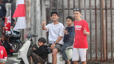 Ulusal bayrak ve elektrikli scooterla poz veren Endonezyalı erkek ve çocuklardan oluşan bir grup, Bağımsızlık Günü 'nü canlı bir sokak atmosferinde kutluyorlar, Bandung - Endonezya, 17 Ağustos 2024