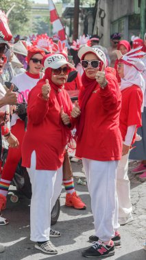 Bir topluluk geçit töreninde coşkuyla kırmızı-beyaz giyinmiş bir grup katılımcı kültürel ruh ve birlik sergilediler, Bandung - Endonezya, 17 Ağustos 2024