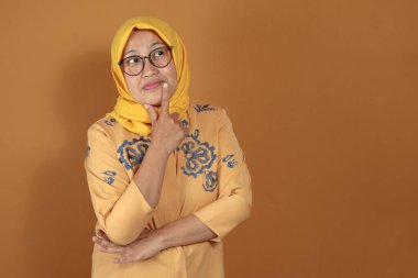 Yüzünde düşünceli bir ifade olan gözlük takan son sınıf öğrencisi bir kadının karar verme, planlama ya da sorun çözme mekanizmasını temsil ettiğini düşünüyorum.