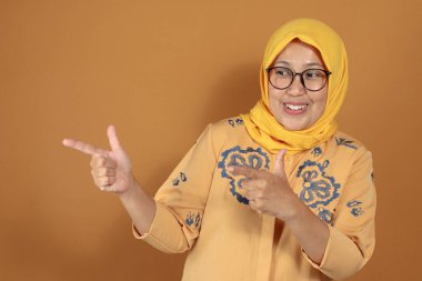 Gülümseyen kadın parmaklarını güven ve pozitif tutumla işaret ediyor.