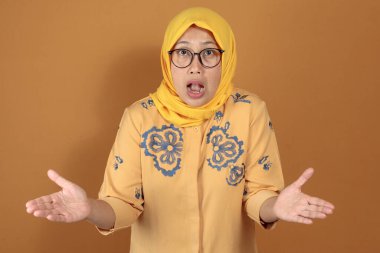 Elleri açık, kafası karışmış yüz ifadesi takınan şaşırmış bir kadın.