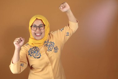 Mutlu Müslüman kadın sevinçli bir ifadeyle yumruk tokuşturarak kutluyor, başarı ya da başarı kavramı için harika.