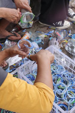 Bandung, Endonezya 29 Nisan 2025, Kadın plastik şişeleri sınıflandırma ve kesme Açık hava kamu geri dönüşüm işi