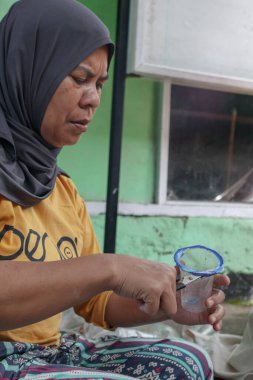 Bandung, Endonezya 29 Nisan 2025, kadın geri dönüşüm sırasında plastik atıkları makasla kesiyor.