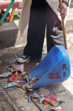Bandung, Endonezya 29 Nisan 2025, ıslak sokakları temizlerken plastik çöpleri mavi faraş içine süpüren insan cesedi.