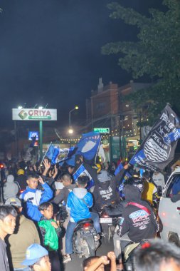 Bandung, Endonezya Mayıs 09 2025: Persib Bandung taraftarları Liga 1 şampiyonluğunu kutlayan motosikletlerle geçit töreni yapıyorlar, sokak mitinginde takım bayraklarını sallayarak spor tutkusu ve toplum gururunu gösteriyorlar