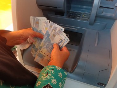 Bandung, Endonezya - 09 Mayıs 2025: ATM para çekme sahnesi Endonezya rupia banknotlarının editoryal kullanım işlemleri sırasında el sayımını gösteriyor