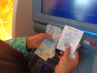 Bandung, Endonezya - 09 Mayıs 2025: ATM makbuzu ve nakit kapanış Endonezya 'da para çekilmesinden sonra bankacılık faaliyetlerini ve mali işlemleri gösteriyor