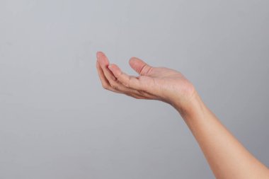 Hafifçe kavrulmuş insan eli, parmakları gevşemiş şekilde yukarı kaldırılmış. Düz arkaplanda doğal duruşu olan, soru sormayı, sunmayı ya da manevi ifadeyi sembolize ediyor.