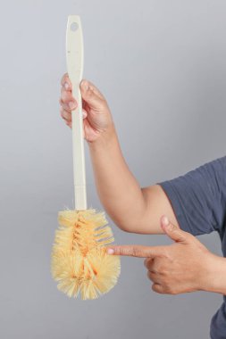 El ele tutuşup hijyen için sarı kıllı temizlik fırçasına işaret ediyor.