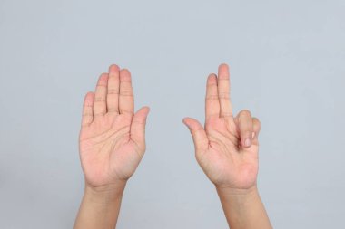 Sekiz numarayı gösteren iki el, bir avuç içi açık diğer üç parmak, parmak sayma hareketi ve görsel sayı gösterimi olarak gri arka plana karşı kaldırılmış.