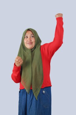 Kendine güvenen tesettürlü kadın zafer için elini kaldırıyor, güç ve kararlılık gösteriyor. Kazanma, liderlik ya da kutlama gibi konular için mükemmel.