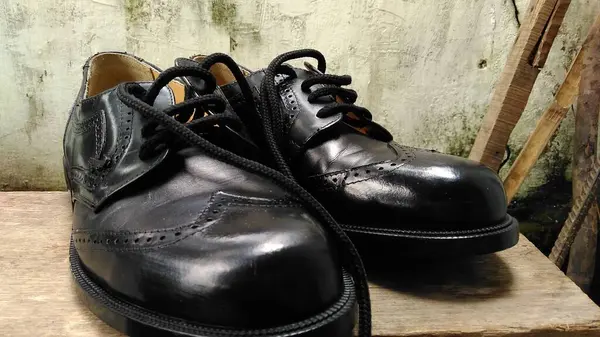 Tahta bir kutuda oturan siyah bir çift ayakkabı.