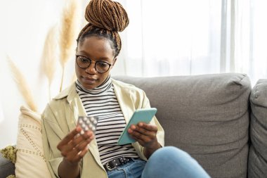 Gülümseyen Afro-Amerikan kadın cep telefonu tableti. İnternette ilacın ilacını araştırıyor. 