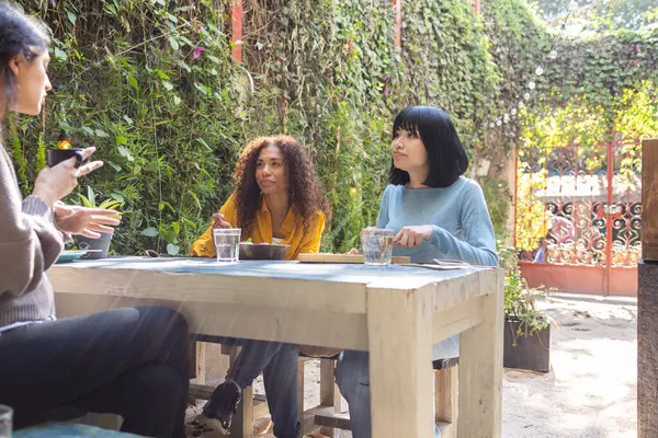 Diverse friendship, three women talking at the garden while having a lunch