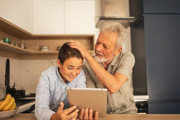 Loving Grandfather Stroking Grandsons Head Using Digital Tablet Kitchen Home — Stock Photo, Image