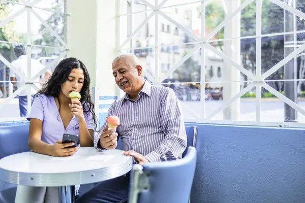 Menina Adolescente Seu Avô Usando Tecnologia Enquanto Desfruta Sorvete Foto — Fotografia de Stock