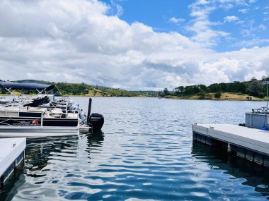 Güneşli bir günde bulutlu bir gökyüzünün altında yeşilliklerle çevrili güzel bir göl görüntüsü. Pardee rezervuar eğlence alanı CA, ABD