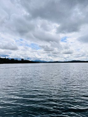 Güneşli bir günde bulutlu bir gökyüzünün altında yeşilliklerle çevrili güzel bir göl görüntüsü. Pardee rezervuar eğlence alanı CA, ABD