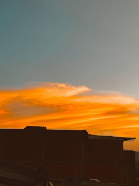 Turuncu gökyüzü ile güzel bir gün batımı ve Manrique mahallesinden büyük bir bulut görünüyor. Medellin, Antioquia, Kolombiya.