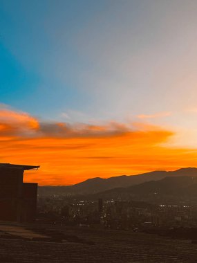 Turuncu gökyüzü ile güzel bir gün batımı ve Manrique mahallesinden büyük bir bulut görünüyor. Medellin, Antioquia, Kolombiya.