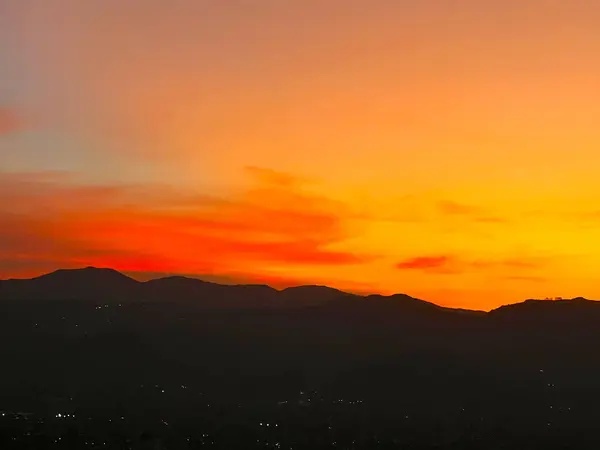 Turuncu gökyüzü ile güzel bir gün batımı ve Manrique mahallesinden büyük bir bulut görünüyor. Medellin, Antioquia, Kolombiya.