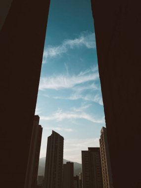 Gökyüzü bulutlu ve mavi gökyüzü pencereden görülüyor. Medellin, Antioquia, Kolombiya.