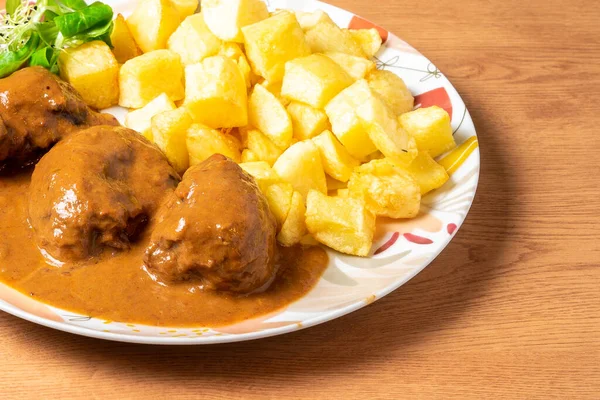 Ahşap masada patates kızartması ve soslu köfte tabağı. Yüksek kalite fotoğraf