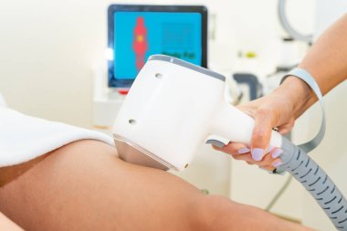 Laser depilation. Midsection of female beautician using laser machine on customers leg at salon. High quality photo