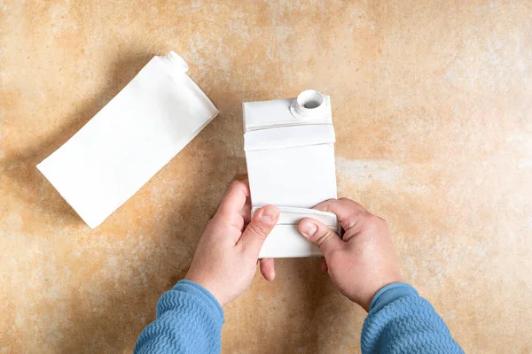 Person folding tetra pack carton ready to be recycled . High quality photo