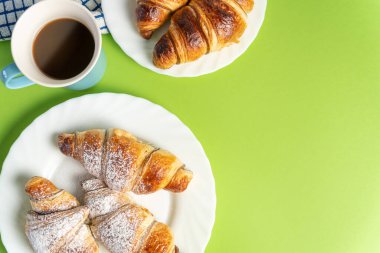 View from the top of a delicious chocolate croissant with a cup of coffee on a colorful background. High quality photo