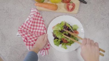 Kadın elinin yukarıdan görünüşü taş masanın üzerinde ahşap maşayla lezzetli taze salata topluyor. Sağlıklı gıda konsepti. - Evet. Yüksek kalite fotoğraf