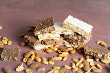 Çikolata, badem ve fıstık katmanlarının yer aldığı çeşitli nougat çikolatalarının yakın plan görüntüsü, arduvaz, gösterişli doku ve çeşitlilikte sıralanmış.