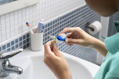 Genç bir çocuk diş fırçasıyla diş fırçasını temizliyor, banyo aynasında görülüyor, kişisel hijyen ve diş bakımına odaklanıyor.