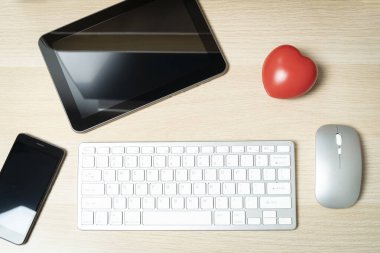 Tabletli ofis masası, akıllı telefon, klavye, fare ve kırmızı kalp iş aşkını gösteriyor
