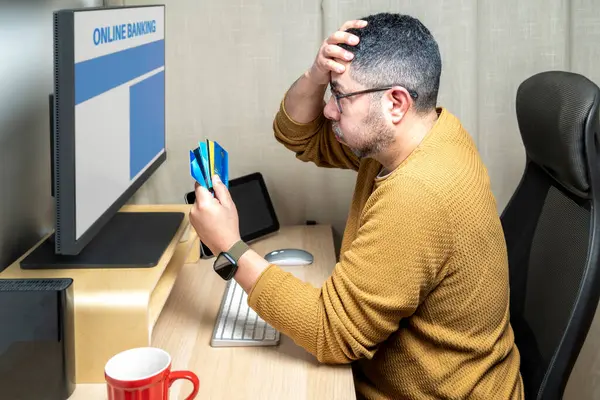 Kredi kartı tutan endişeli bir adam ve online bankacılık ile ilgili sorunları var.