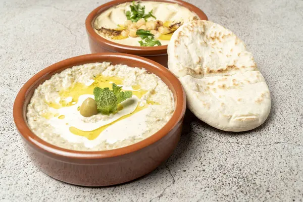 Lezzetli orta doğu sosu, baba ghanoush ve humus, Pita ekmeği, zeytinyağı ve taze bitkilerle servis edilir.