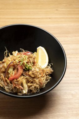 Buharlı pancit bihon, filipino erişte tabağı, tavuk, sebze ve limon dilimi ile servis edilir.