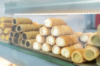 Çeşitli tatlarla dolu taze pişmiş kremalı börekler, fırın vitrinindeki ahşap bir tepside güzelce düzenlenir.