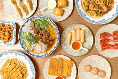 Erişte, çorba, börek, kızarmış pirinç, gyoza ve seramik tabaklar üzerinde ahşap bir masa üzerinde düzgün sıralanmış tatlılar da dahil olmak üzere çeşitli Asya yemeklerinin en üst görüntüsü..