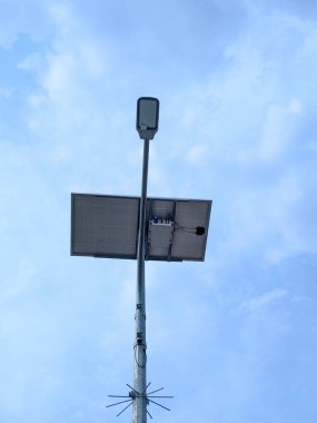 Modern tasarımı ve açık mavi gökyüzü olan güneş enerjili sokak lambası. Güneş paneli, LED lambasının tam üstüne monte edilmiştir..