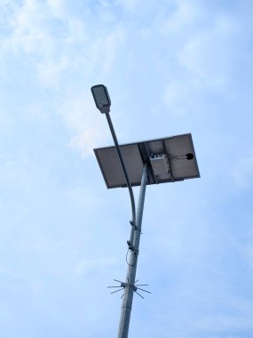 Modern tasarımı ve açık mavi gökyüzü olan güneş enerjili sokak lambası. Güneş paneli, LED lambasının tam üstüne monte edilmiştir..