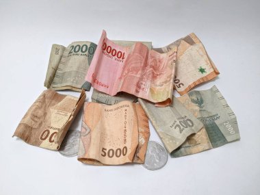 Endonezya paralarının ve paraların saçılması. Görünür değerler arasında 1000, 2000, 5000 ve 10000 rupiah 'lık banknotlar ile birlikte birkaç bozukluk bulunur. Notalar biraz yıpranmış gibi görünüyor..