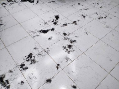 Beyaz fayanslı zemine saçılmış siyah insan saçı. Berber dükkanlarında ve salonlarda sık görülen bir manzara..