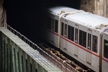 Şehir treni karanlık tünele giden çelik köprüyü geçiyor.